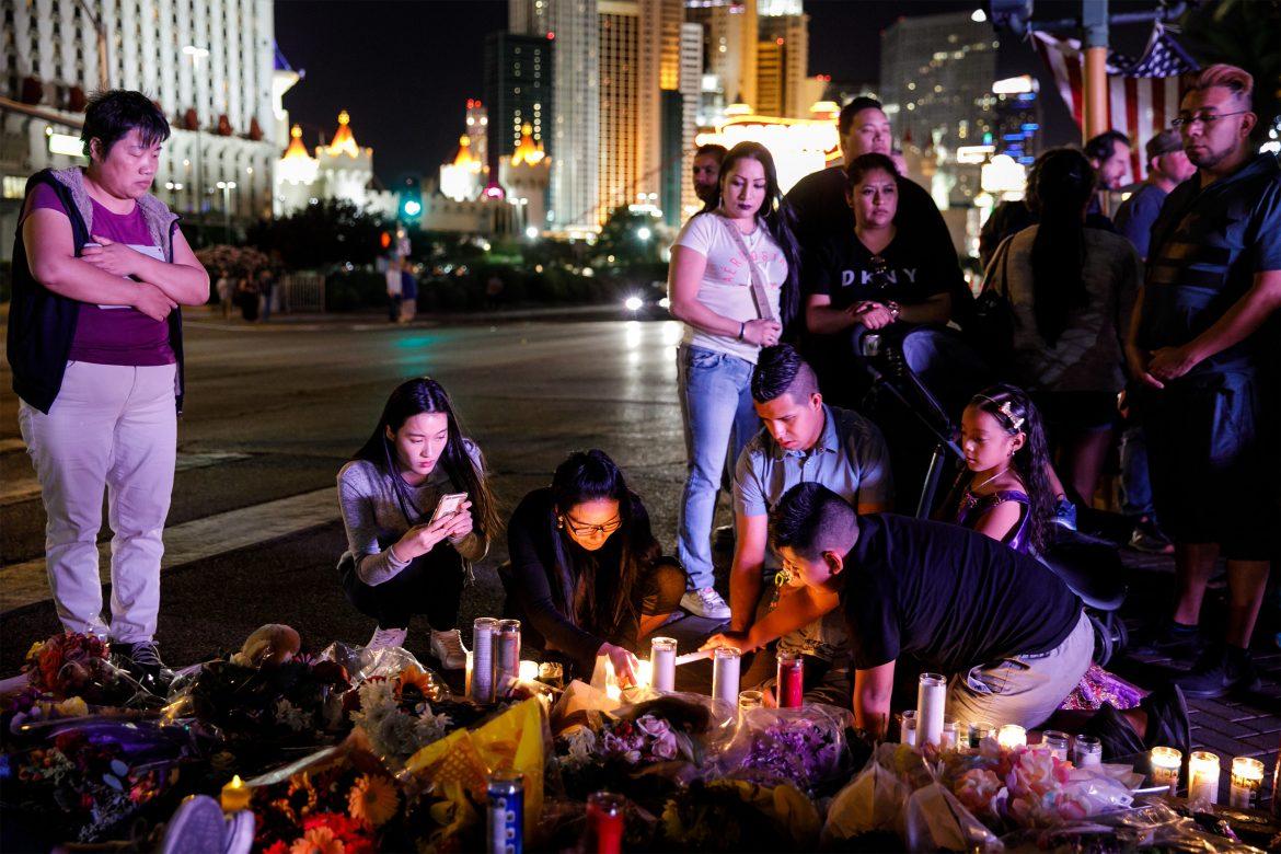 crowd on Las Vegas strip in front of candles and flowers on the floor