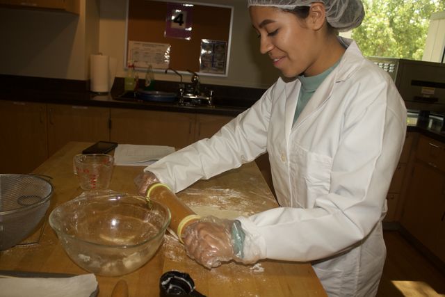 woman in white overcoat with hair up in hairnet holding brown roller
