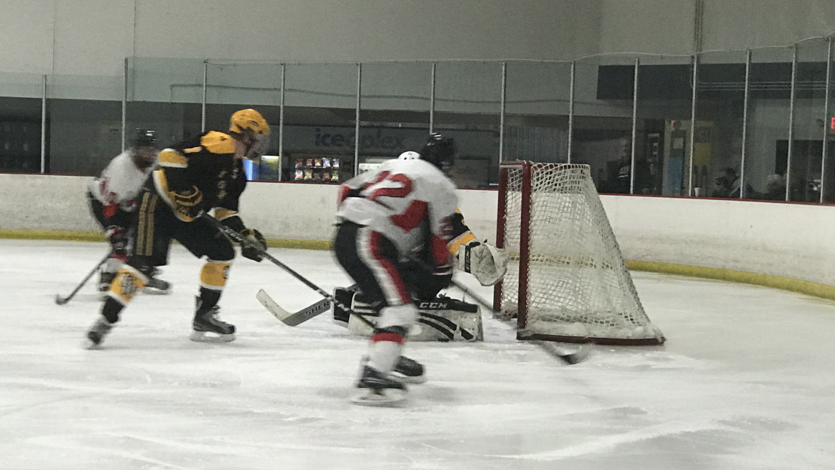 CSUN hockey player in white red and black playing against black and yellow team