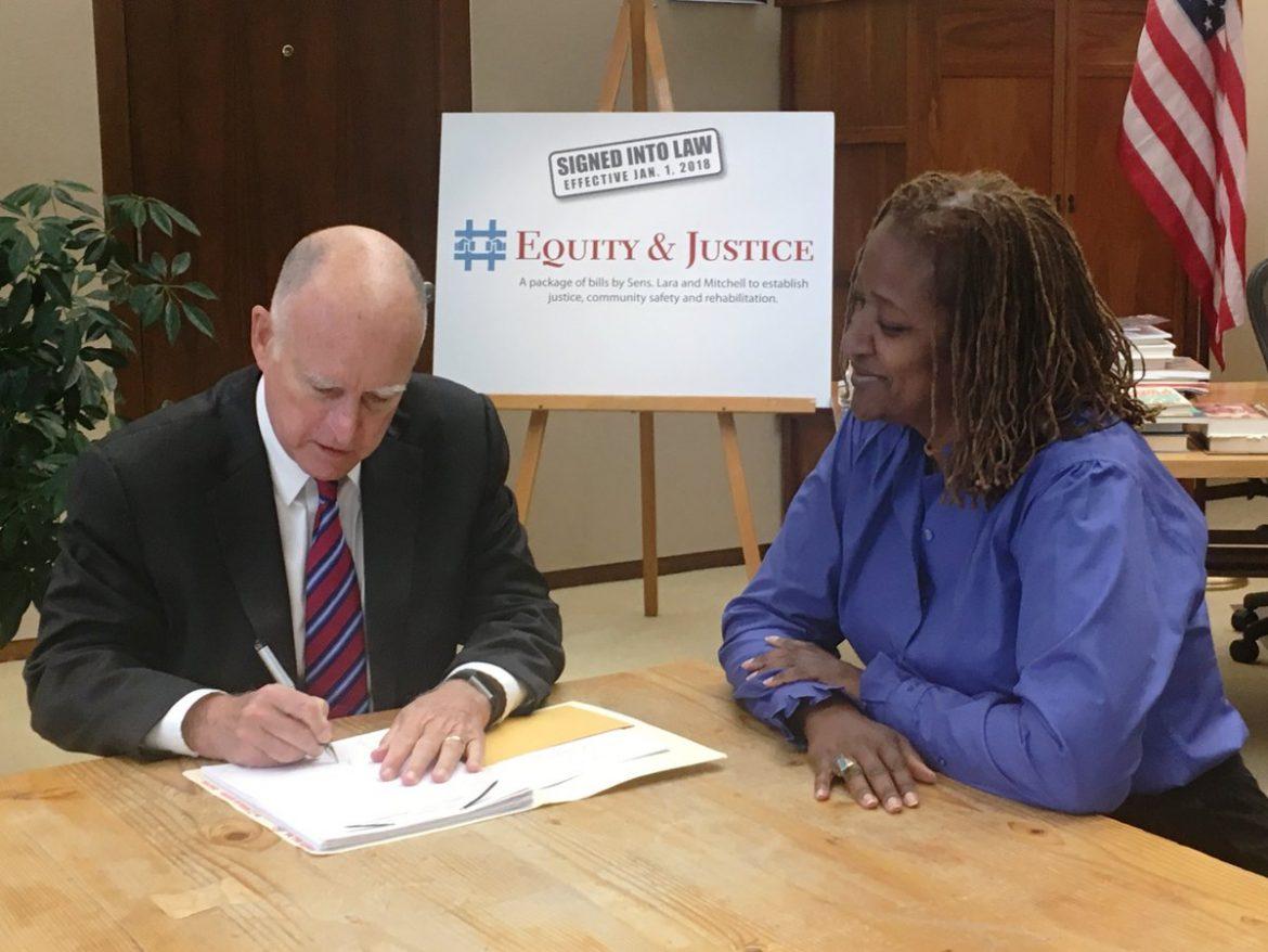man in black suit and red tie signing a paper. woman in blue blouse