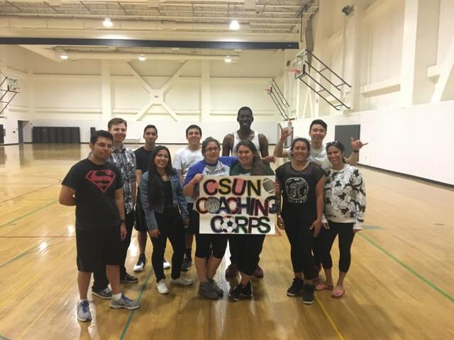 men+and+woman+holding+a+sign+reading+CSUN+Coaching+Corps