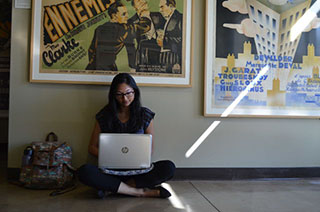girl sitting on floor with laptop above her a movie poster