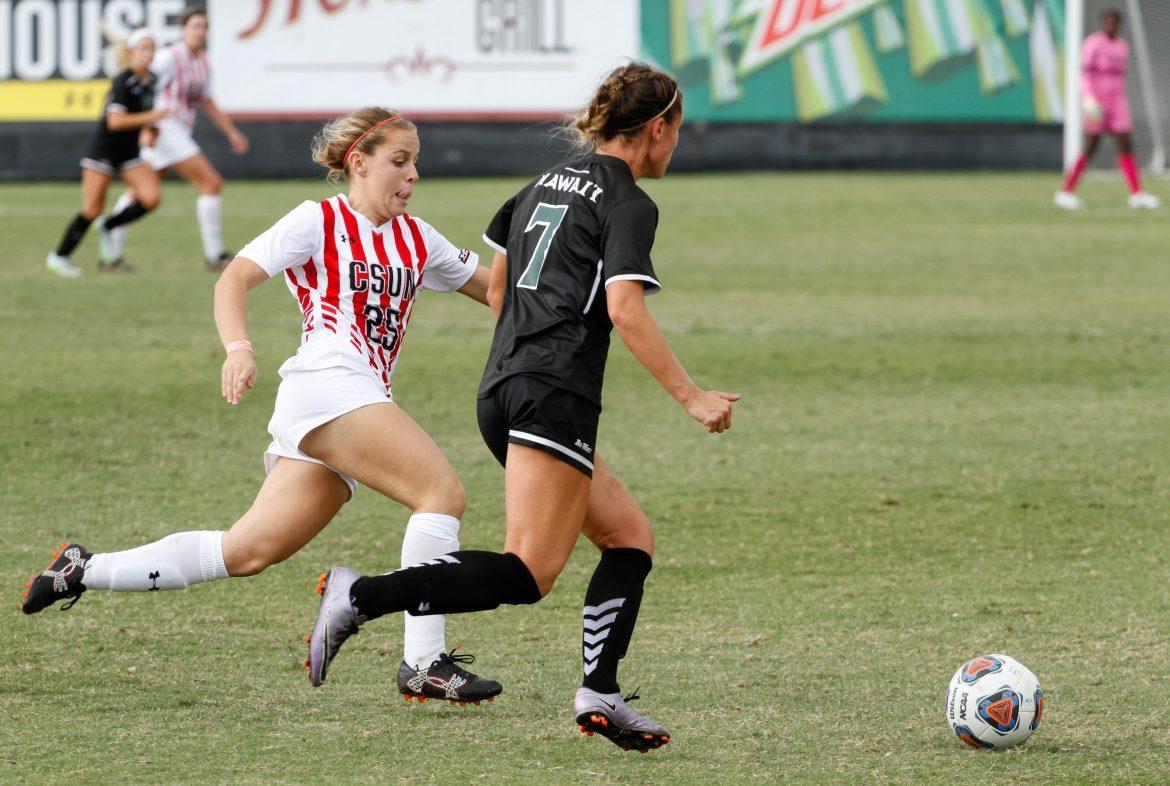 CSUN female soccer player in white and red running with determined face