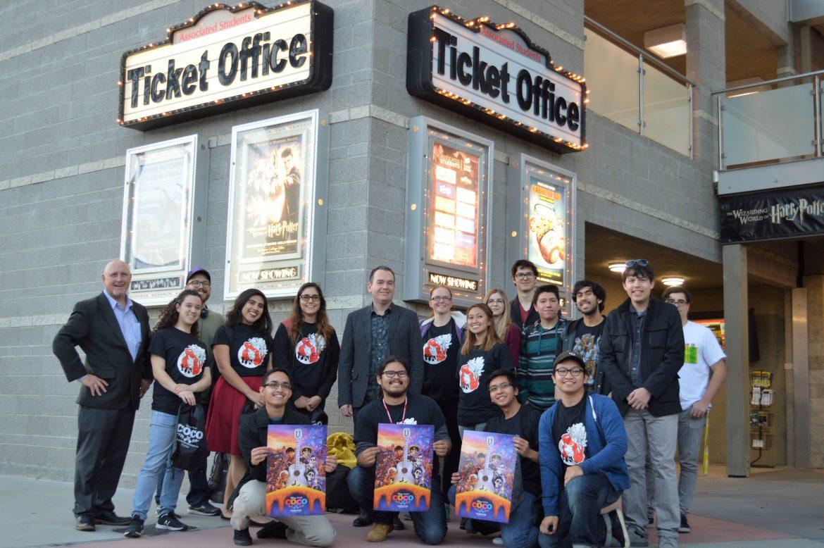 people stand in front of ticket office and some hold COCO movie posters