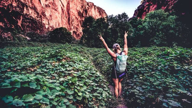 girl posing in green filed surrounded by rust colored rock formations
