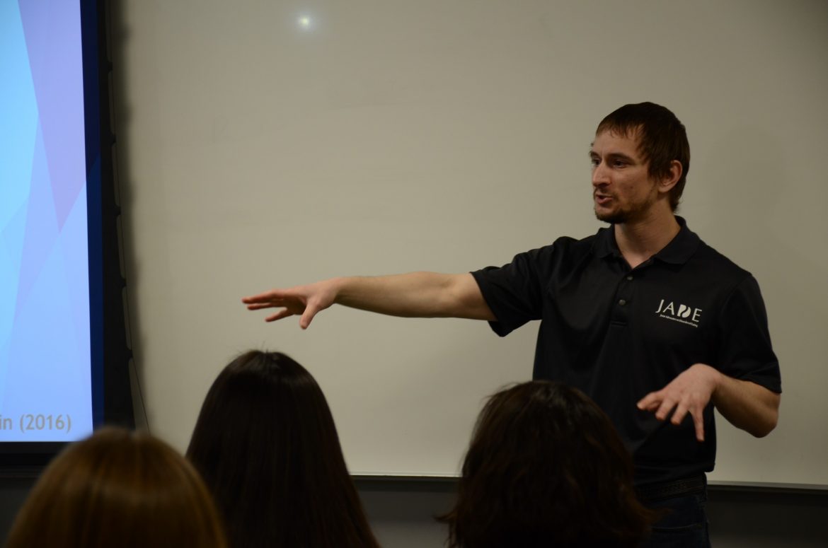 Man+in+black+shirt+speaking+to+students+inside+of+a+classroom