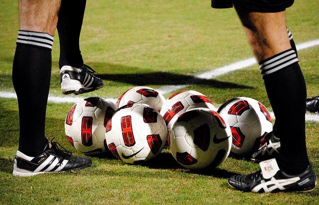 soccer balls on field with referees surrounding them