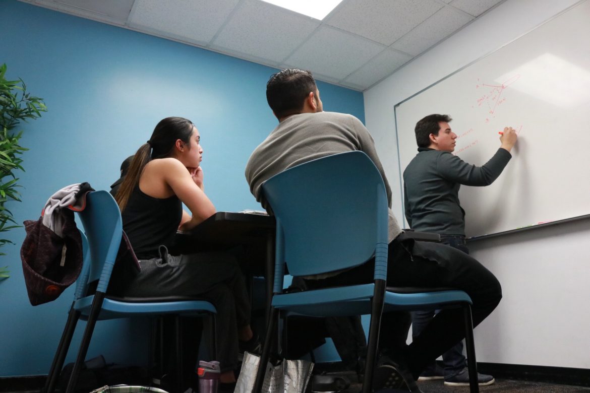 students sit focused while watching a man work on the board