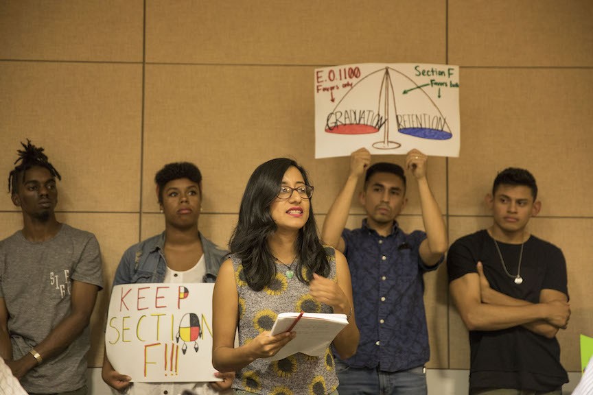 students hold signs of protest to keep section F