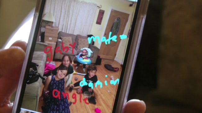 picture of a picture on a phone of 4 young children playing in a living room