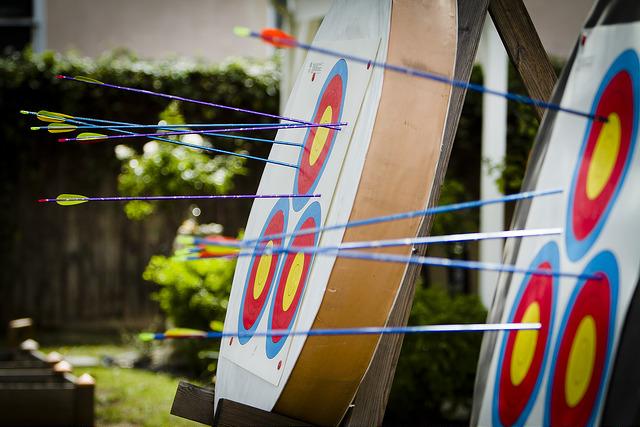 blue and purple archers arrows embedded in red yellow and blue circular targets