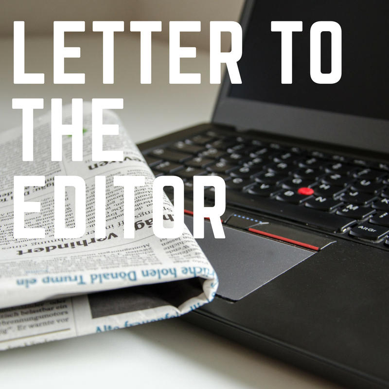 large bold white lettering in front of a black laptop and a newspaper