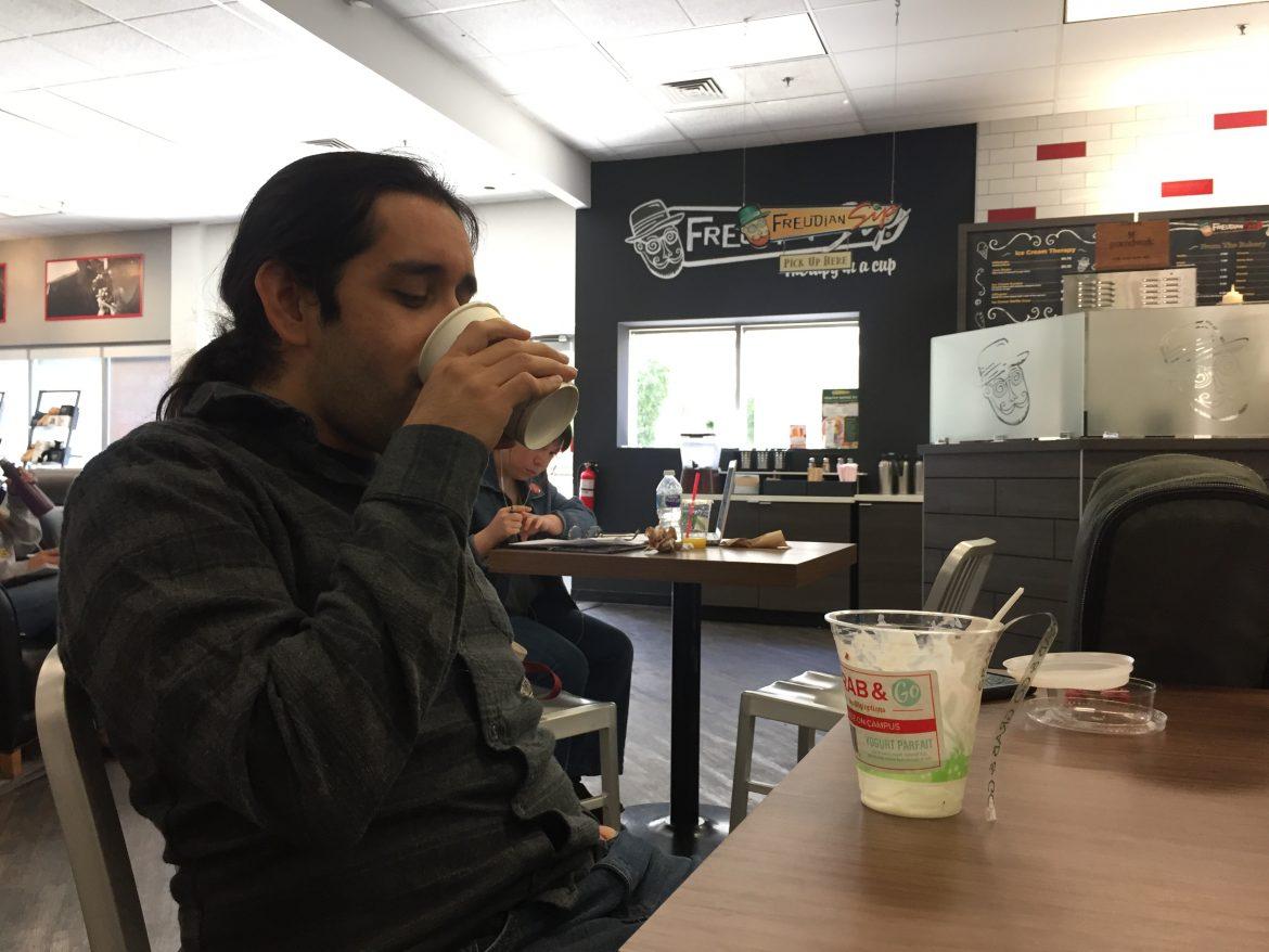 man sits at table and sips coffee