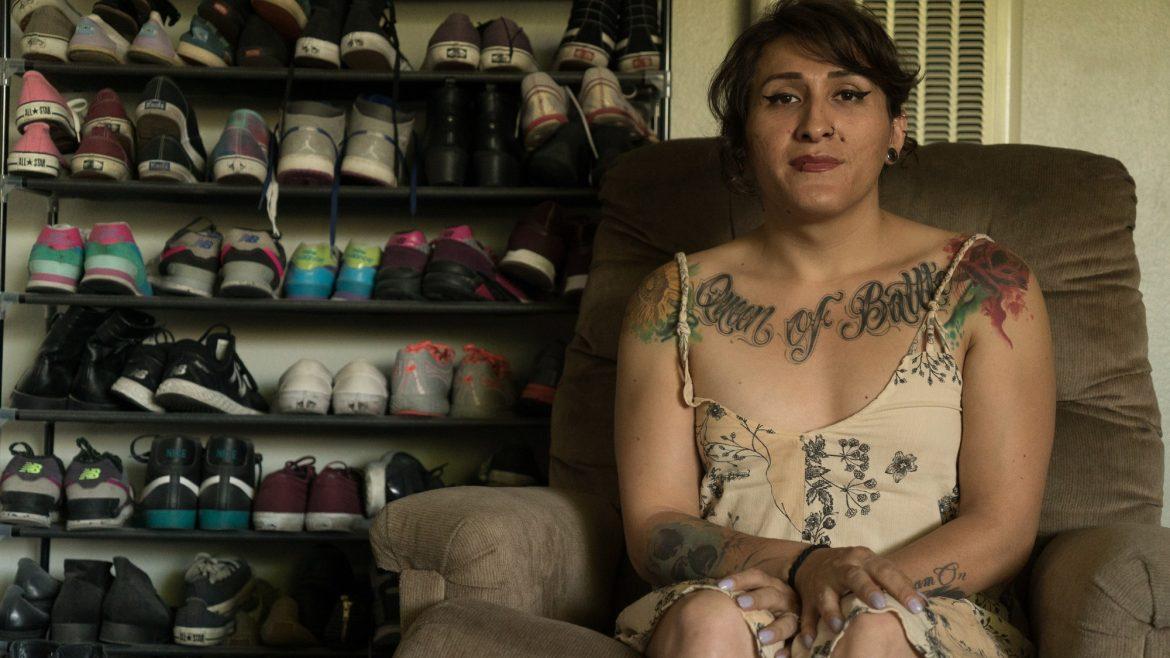 woman sits on recliner with racks of shoes behind her