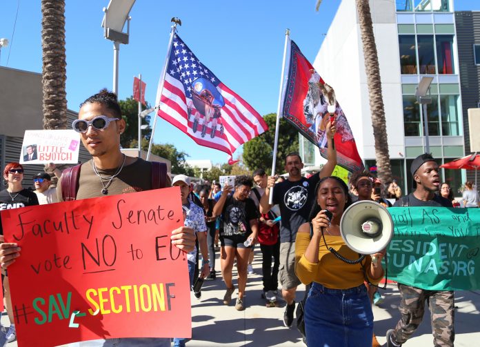 CSUN Politcal Science Pre-Law major, and Vice President of the Black Student Union, Isaiah Thibodeaux (left) holds up a sign as he marches to protect school Section F from Executive Order 1100 at the University Student Union in Northridge Calif., Wednesday, October 25, 2017. ( John Hernandez / The Sundial)