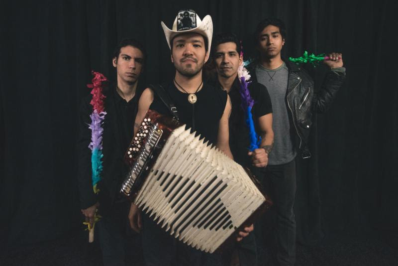 four men stand seriously with piñata sticks and an accordion