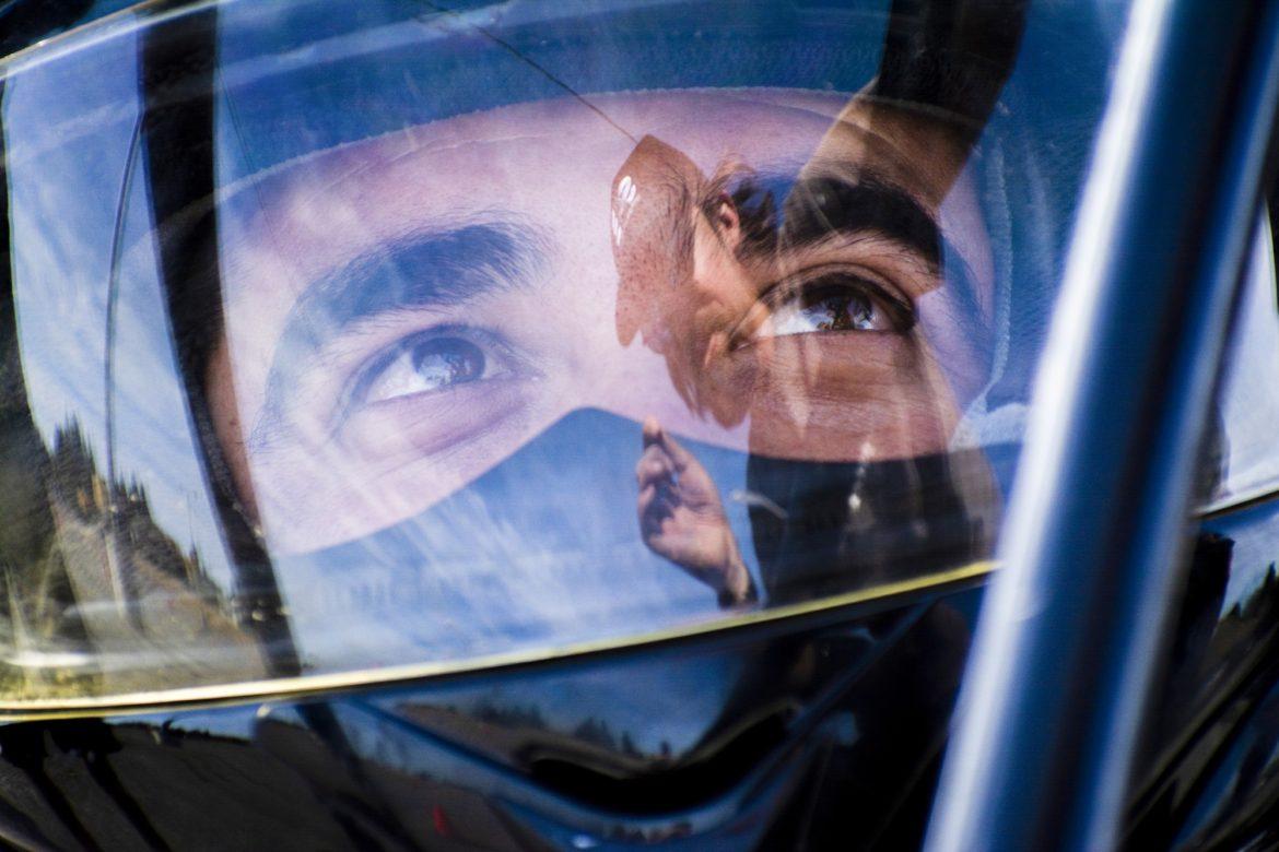 A male driver in his helmet looking at his coach.