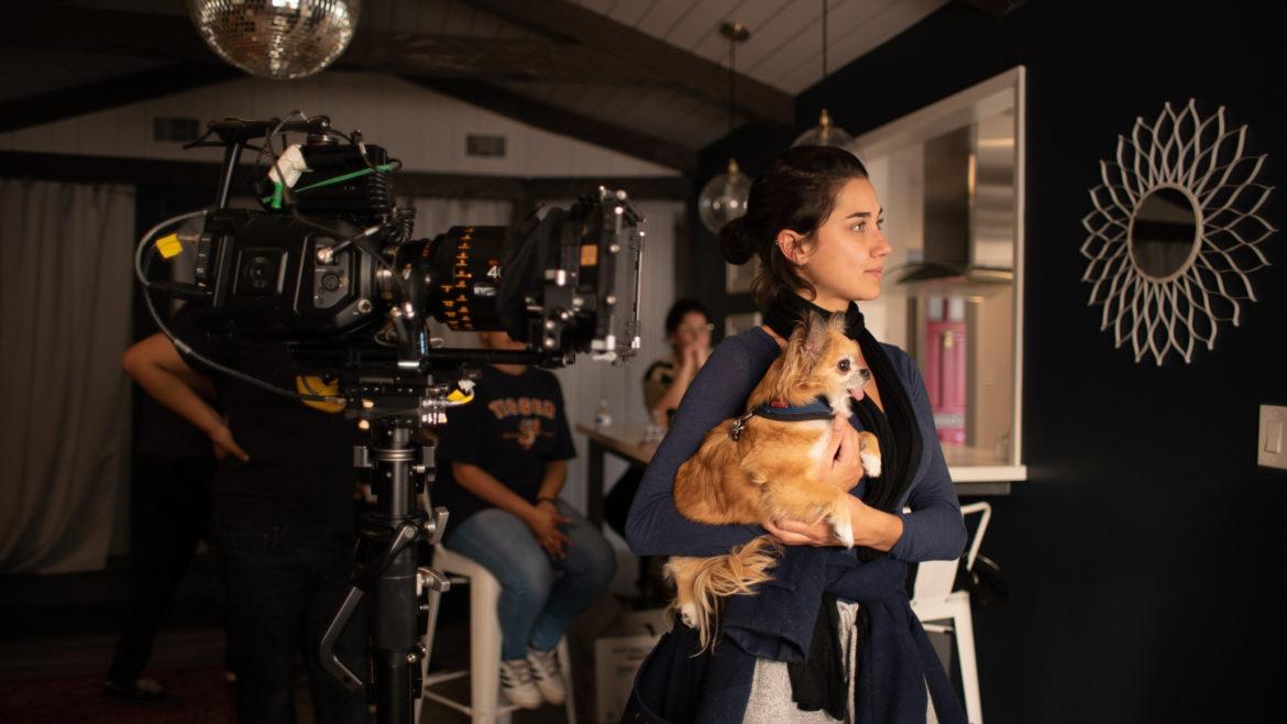 An actress filming with a dog in her arm.