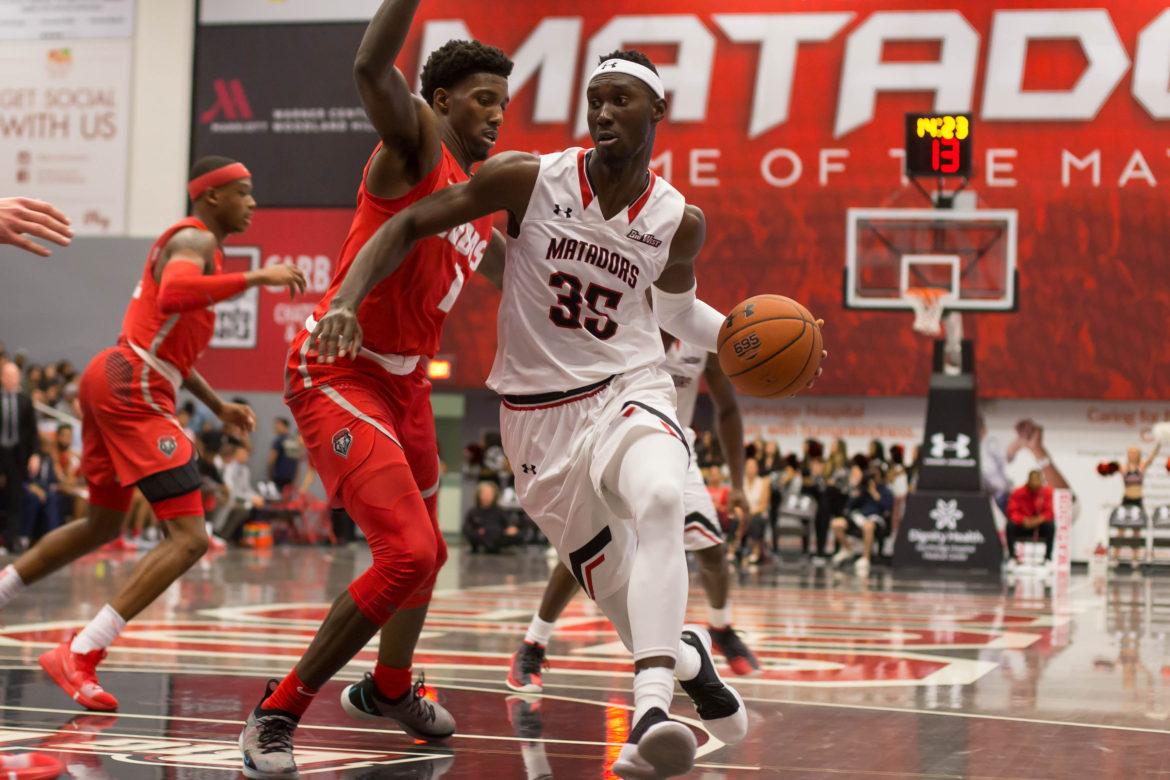 A CSUN Men's basketball player trying to get passed over the defender and score