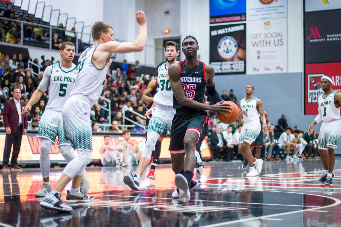 Freshman Lamine Diane attempts to go around a Cal Poly defender on his way to the basket in the win over the Mustangs on Saturday. Diane got his 13th double-double of the season, recording 22 points and 11 rebounds in just 22 minutes. Photo credit: John Hernandez