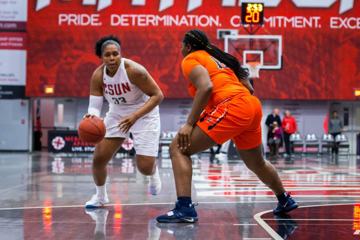 A CSUN Womens basketball play in wihte jersey handing the ball to get pass a denfender in orange jersey.