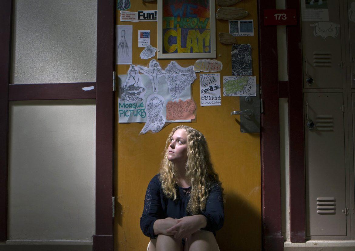 A female student sitting right next at a locker