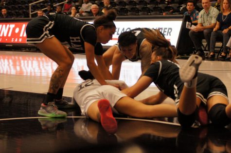 Four women's basketball players diving on the floor for the ball