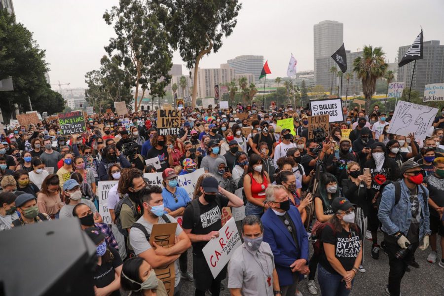 A crowd of protesters listening to Melina Abdullah, co-founder of Black Lives Matter L.A., as she performs a libation for the lives lost to police brutality in front of the LAUSD headquarters in downtown Los Angeles on Tuesday, June 23, 2020.