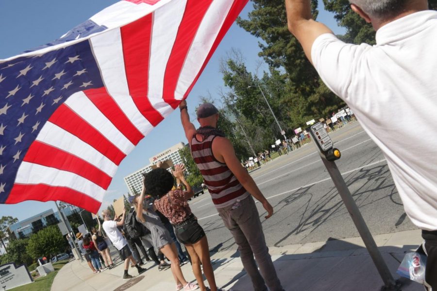 Protesters hold up an American flag upside down.