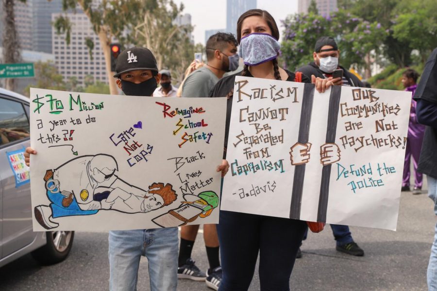 Xavier Recarte (left) and his mother, Maria Recarte hold signs in support of the rally to defund the Los Angeles School Police Department on June 23.