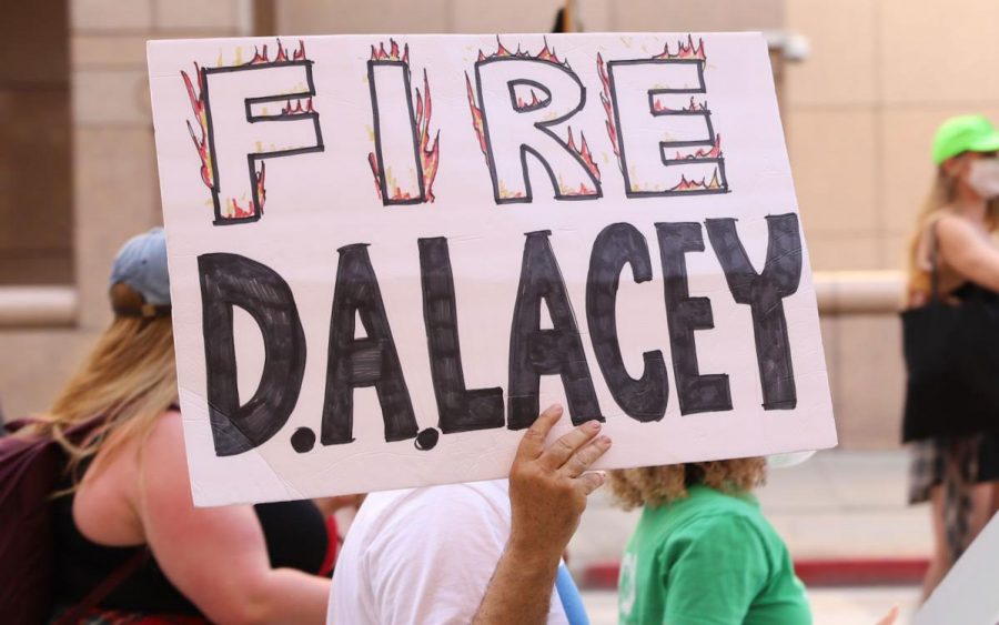 A protester holds up a sign saying fire D.A. Lacey during a BLM protest against the district attorney, Jackie Lacey. Jackie Laceys husband, David Lacey, is charged with three counts of misdemeanor assault with a firearm on  Tuesday.