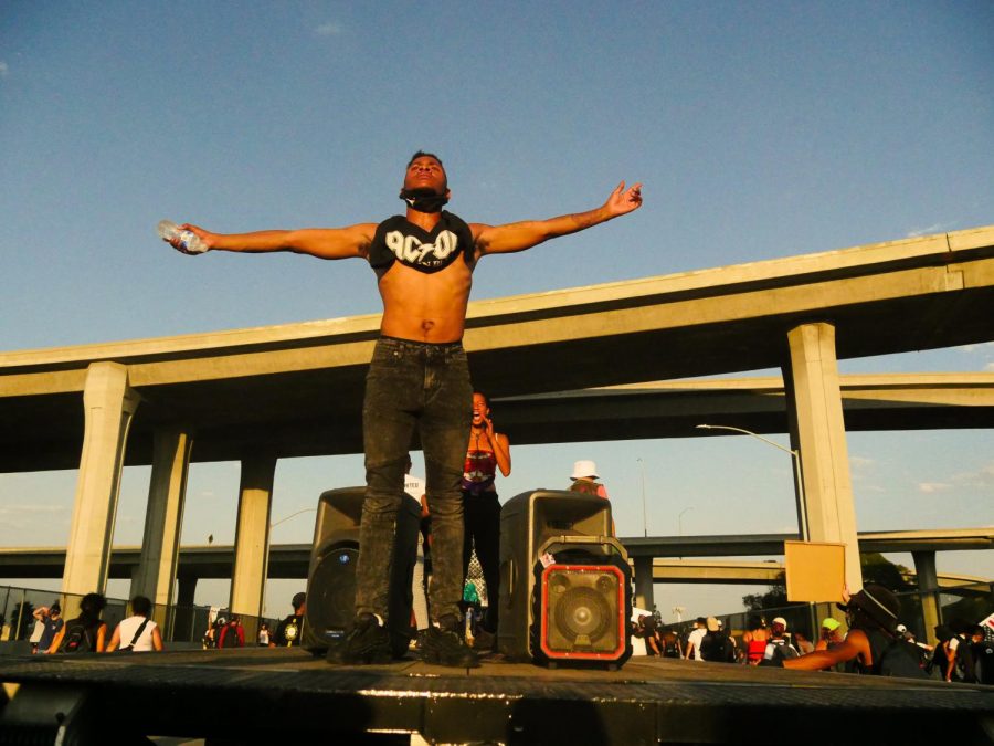 A man stands on a flatbed truck facing protesters as they march down Imperial Highway in South Los Angeles, Calif. on Saturday, Sept. 5, 2020.