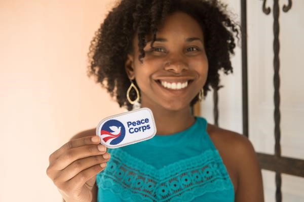 Smiling woman holding Peace Corps badge