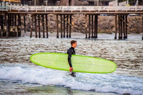A surfer walks into the water at Surfrider Beach next to the Malibu Pier on Tuesday, Feb. 16, 2021.