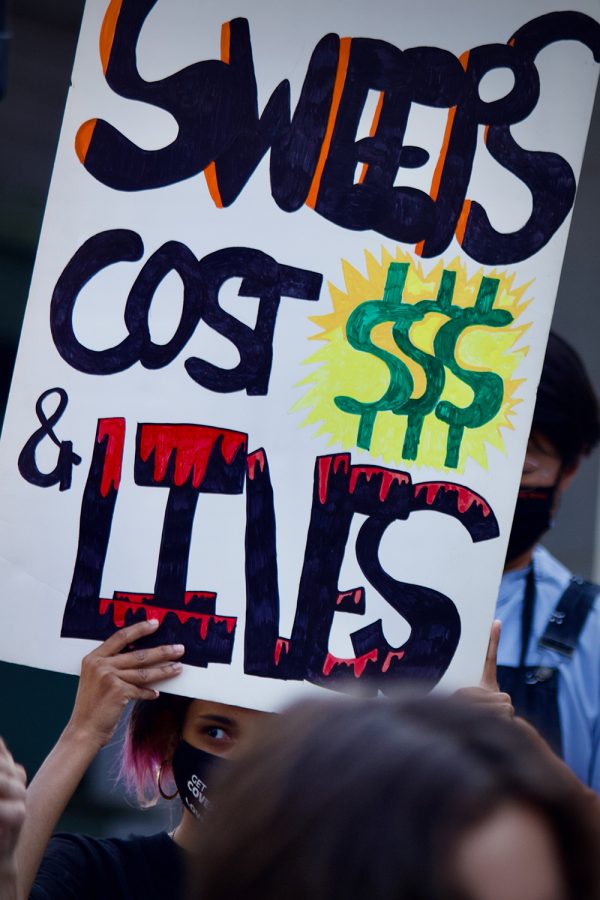 A demonstrator holds a sign reading “Sweeps Cost Lives” at a rally in opposition of a proposed amendment to LA Municipal Code 41.18 on the steps of Los Angeles City Hall on Wednesday July 28, 2021 in Downtown Los Angeles, Calif. Cleanings, referred to as “sweeps” are often not conducted on a routine schedule, and in many cases have Law Enforcement present. Unhoused residents are provided a set amount of time to remove their belongings from a specific location, with items unable to be removed in time destroyed. Mutual Aid organizers across Los Angeles are calling on the city to “Stop the Sweeps”, arguing that cleanups inflict further trauma, and demand the cities resources instead be used towards providing sustainable long term housing solutions.