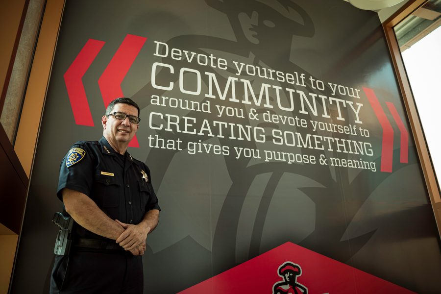 Alfredo Fernandez, the interim Chief of Police at CSUN, stands in front of a mural in the Police Services building. The words on the mural say 