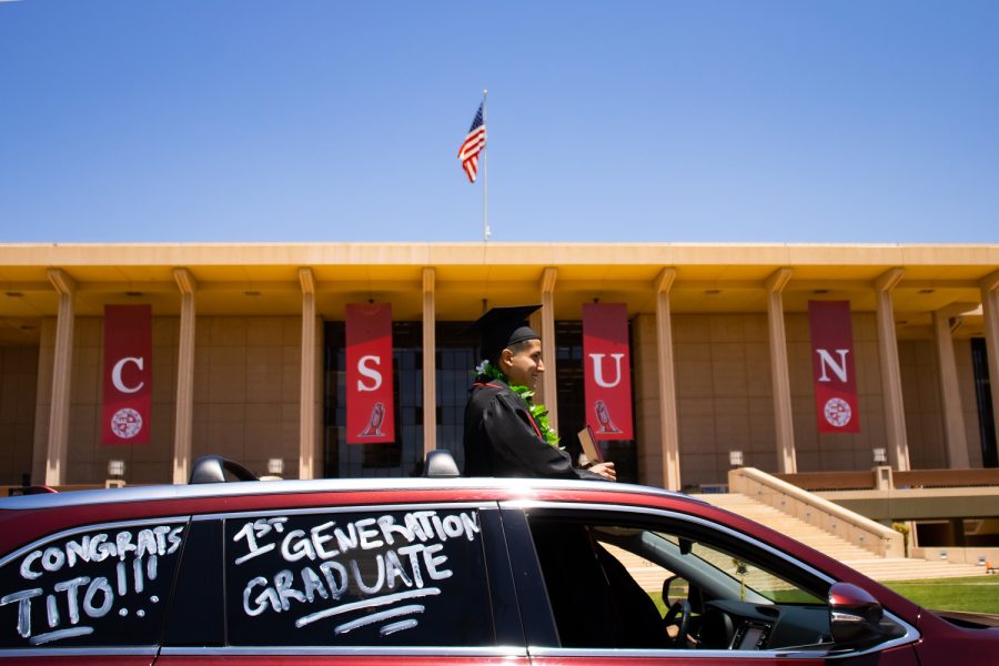 Tito, a first-generation graduate, stands through the sunroof while holding onto his diploma holder in front of the University Library during the CSUN Grad Parade in Northridge, Calif., May 25, 2021.
