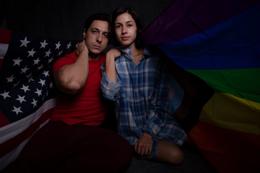 Two people taking a photo illustration with a American flag and the pride flag
