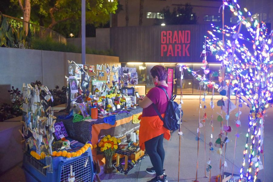 A parkgoer takes a photo of the Crossing Over the Rainbow Bridge community altar at Grand Park in downtown Los Angeles, Calif., on Friday, Oct. 29, 2021.
