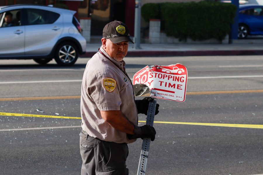 A city employee from the Los Angeles Official Garage Unit picks up the No stopping any time sign from the curb. The sign was struck by the car on Reseda Boulevard in Northridge, Calif., on Friday, Dec. 3, 2021.