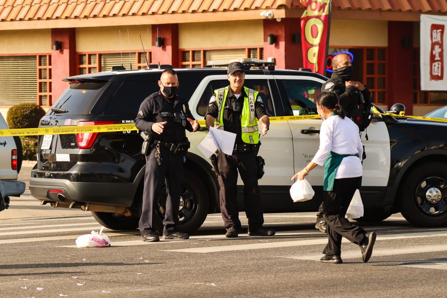 Police officers joke that the food is for them as an A&W Seafood employee delivers a customers order. The customer could not access the restaurant due to the police blockade on Reseda Boulevard and Prarie Street in Northridge, Calif., on Dec. 3, 2021.