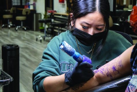 Charleen Quirino outlines a floral tattoo sleeve at Queens of Needles in Northridge, Calif., Oct. 5, 2021.