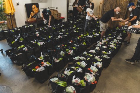 Volunteers put fresh produce into individual grocery bags that will be handed out to the community of South L.A. during South LA Cafes weekly food drive in South Los Angeles, Calif., on March 31, 2021.