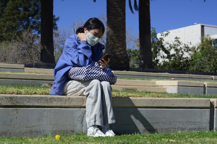 CSUN Sophomore India Sides checks her phone in between classes on the library steps on February 28th, 2022 in Northridge, Calif.