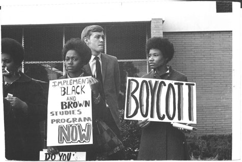 A image of a student back in 1968 holding a sign written BOYCOTT and Implement Black and Brown studies Program Now