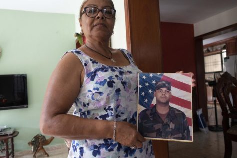 Senora Santos from Washington Heights, New York City, in Santo Domingo, Dominican Republic, with a U.S. Army boot camp portrait of her deported son Juan, July 2018.