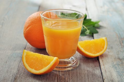 Orange juice in glass with mint, fresh fruits on wooden background