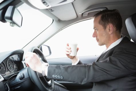 Businessman drinking coffee while driving