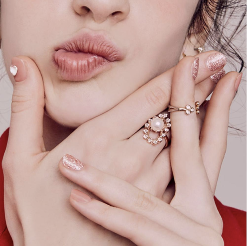 a+woman+with+peach+nail+polish+touching+her+face