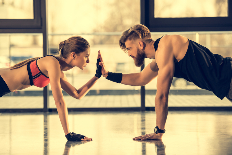 man and woman high-fiving while in plank position